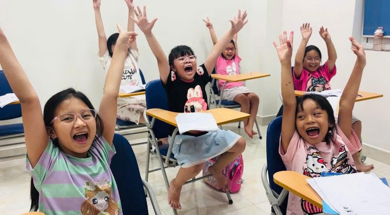 Các bé hào hứng giơ tay trong lớp tiếng Anh